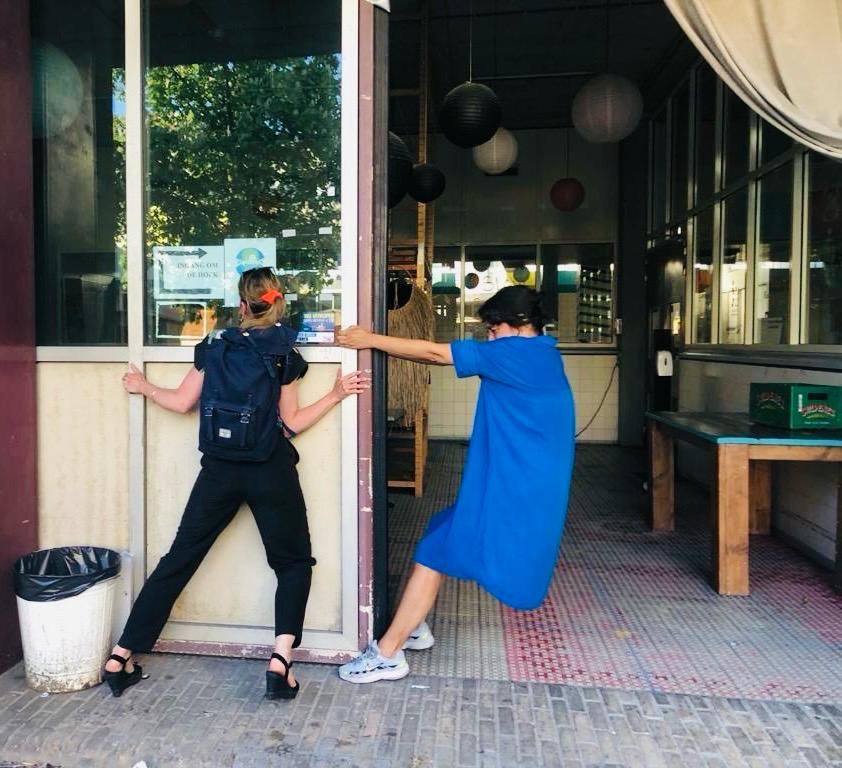 Twee vrouwen die een zware deur dicht proberen te doen.